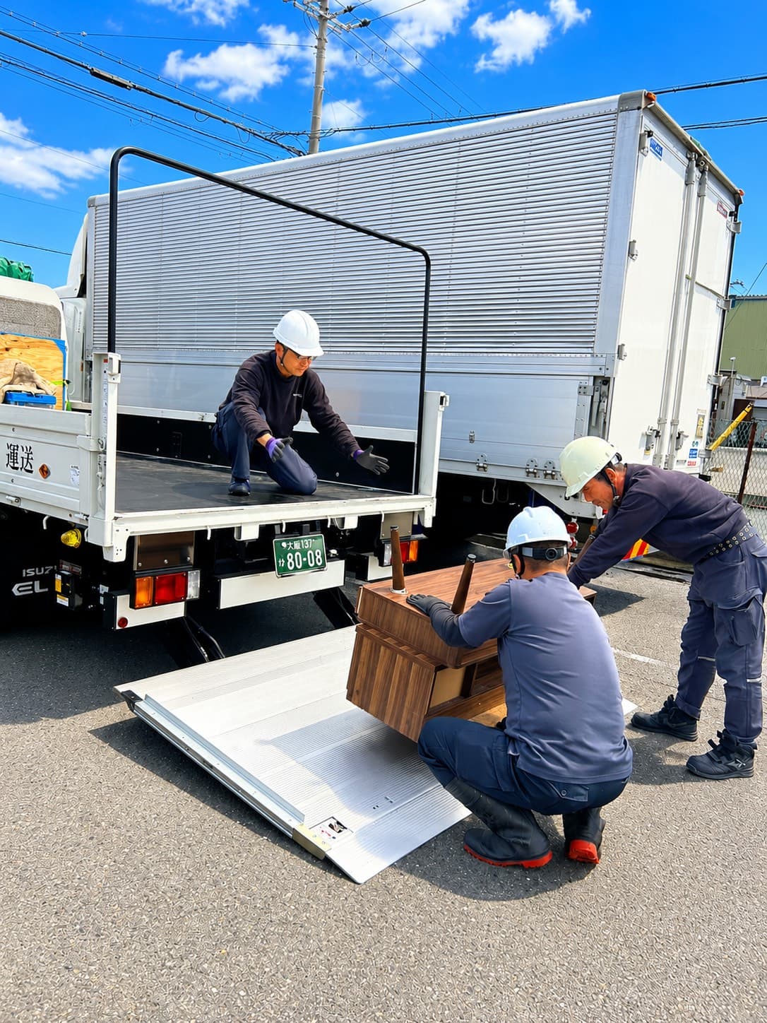 ドライバーが荷台で荷締め作業を行う安全管理の現場写真。